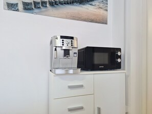 A kitchenette with a coffee machine and a microwave on a white cabinet. - Apartment Emma by Interhome (Krk/Malinska)