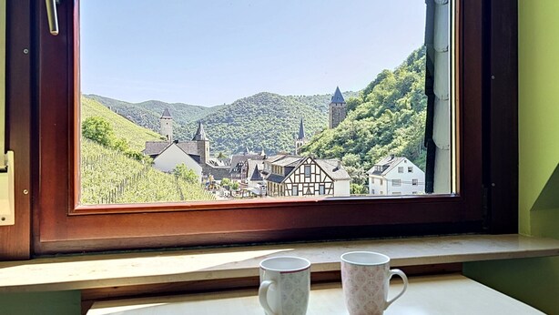 Ein Fenster mit Blick auf eine Stadt, zwei Tassen auf einem Tisch und eine Tür mit Griff.