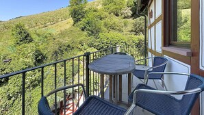 Ein Balkon mit Tisch und Stühlen mit Blick auf eine hügelige Landschaft.
