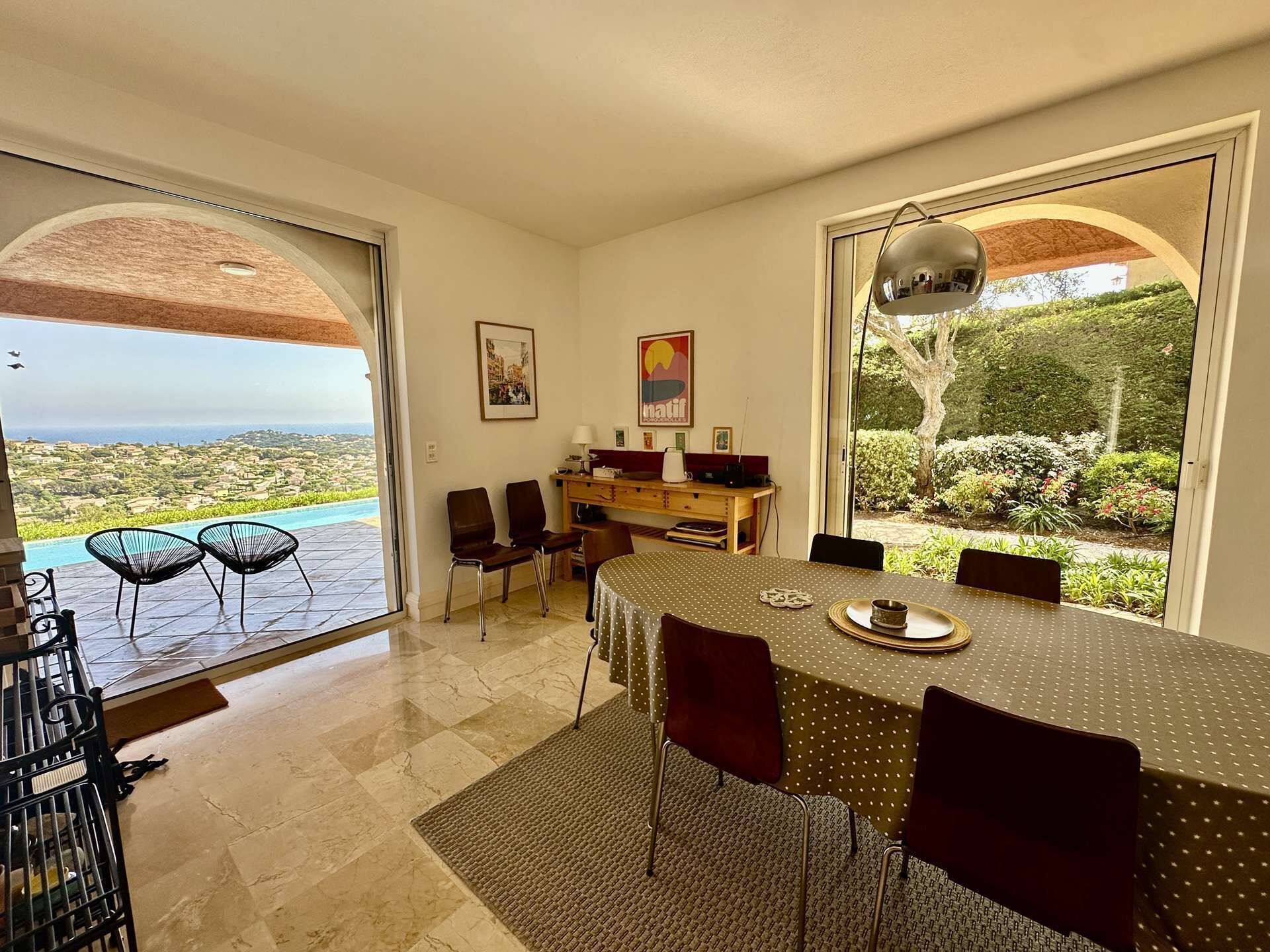 A dining area with a view of the sea, a wooden desk, and a large window.