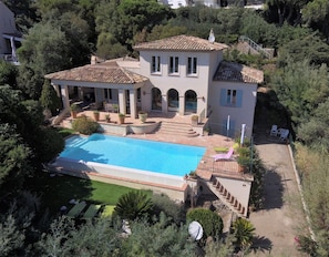Eine Villa mit Swimmingpool, Sitzgelegenheiten im Freien und einem Garten.