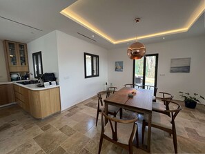 Eine moderne Küche mit einer zentralen Kochinsel, Essbereich mit Holzstühlen und einem großen Fenster.