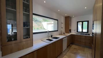 Une cuisine moderne avec des meubles en bois, une grande fenêtre et un lave-vaisselle encastré.