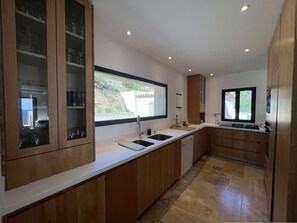 Eine moderne Küche mit Holzausstattung, einem großen Fenster und einem integriertem Geschirrspüler.