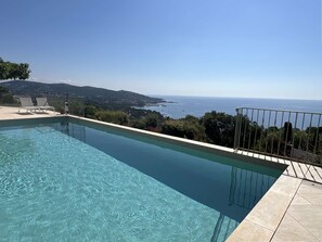 Ein klares Schwimmbecken mit Blick auf das Meer und die Hügel.
