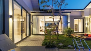 A modern outdoor pool area with lounge chairs, a small garden, and a view into the house. - Wantana villa Sawaree villa 1 V308 (Tambon Si Sunthon)
