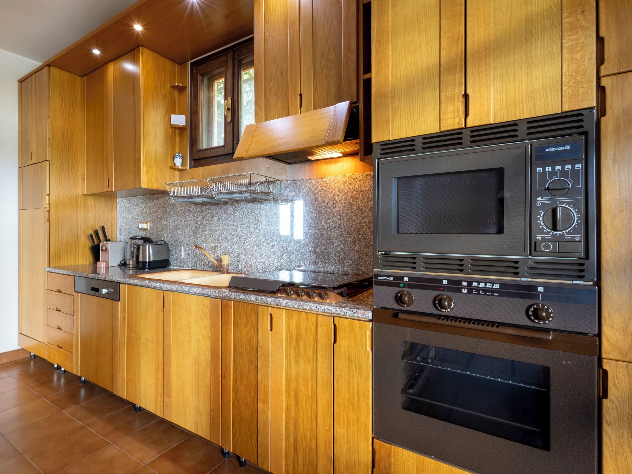 A modern kitchen with wooden cabinets, a granite countertop, a built-in microwave, and an oven.