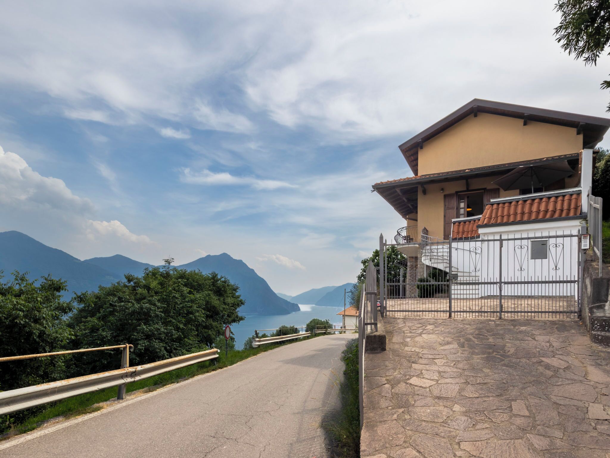 Una casa con un vialetto in pietra che conduce a un cancello, con una montagna sullo sfondo e cielo sereno.