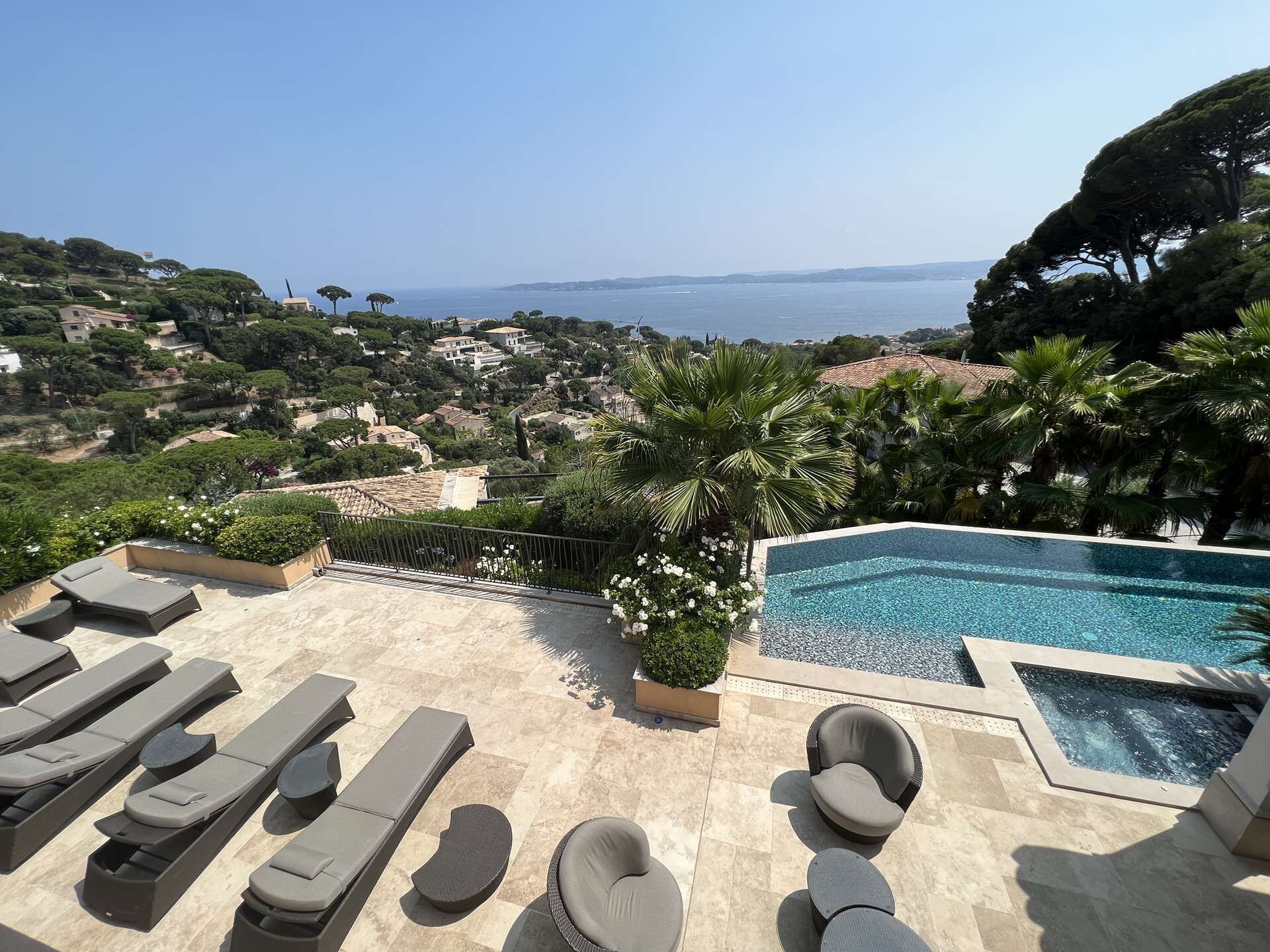 Ein Poolbereich mit Liegestühlen, einem Whirlpool und Blick auf das Meer und die Hügel.