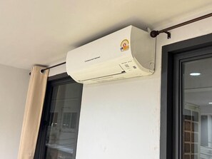 Eine weiße Klimaanlage an einer Wand in der Nähe eines Fensters mit Vorhang.