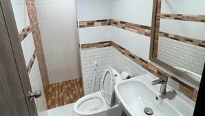 Et badeværelse med toilet, håndvask og spejl.
