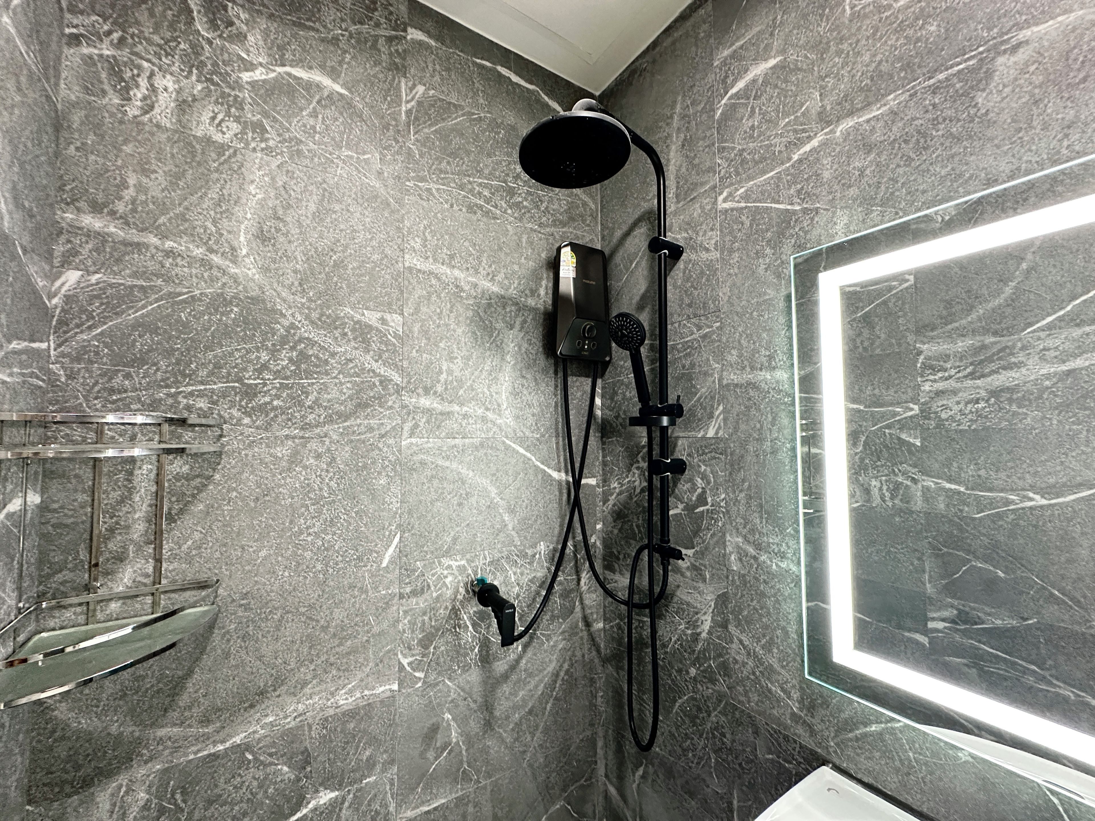 Un bagno con doccia, uno specchio e una parete in marmo.