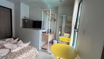 Une chambre d’hôtel de taille réduite, comprenant un lit, une petite table, une chaise, un coin cuisine et une salle de bain.