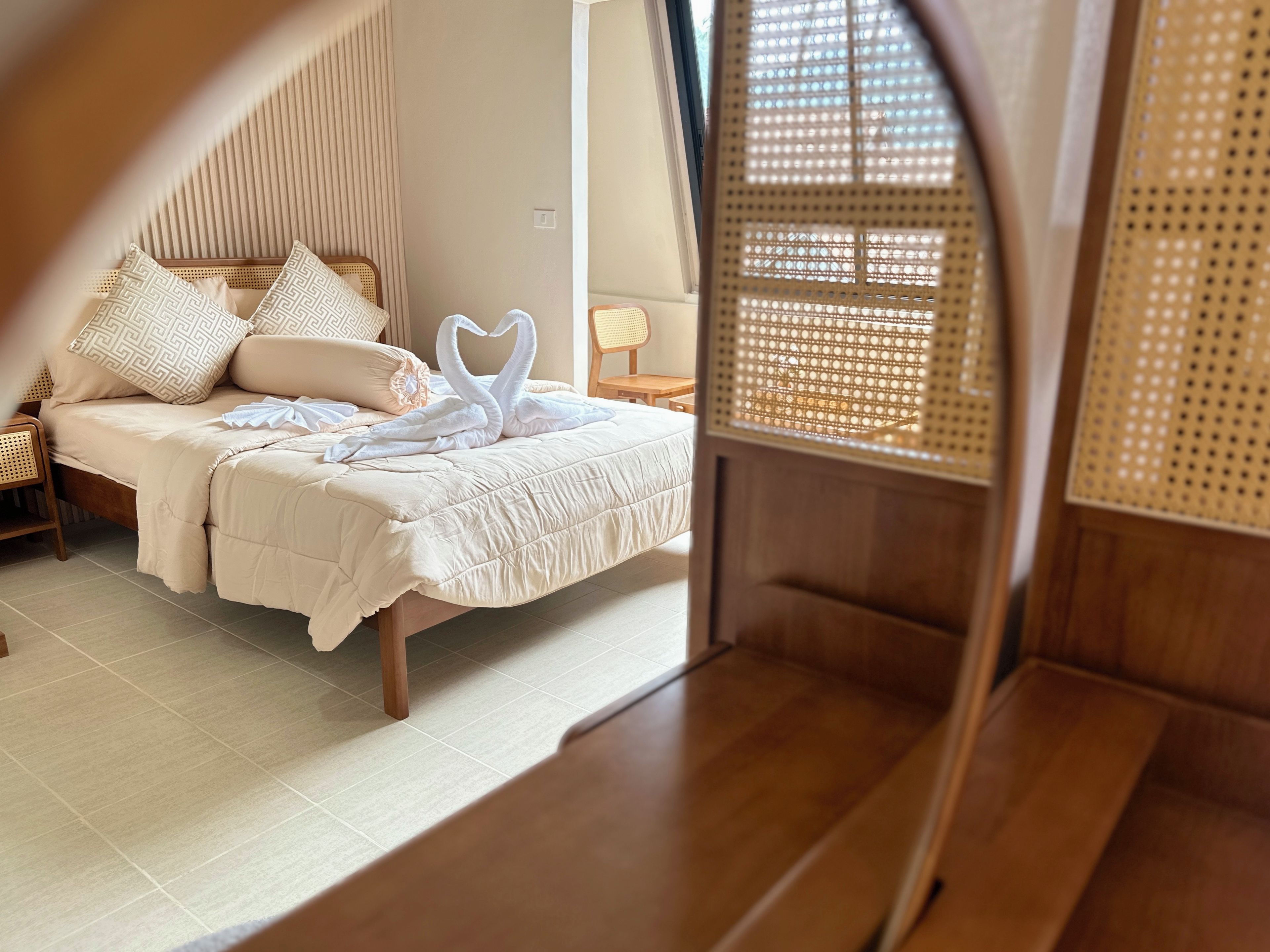 Ein Zimmer mit einem Bett, einer Holzbank und einem Fenster mit einem gewebten Rollo.