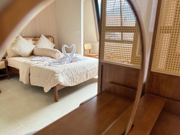 A room with a bed, a wooden bench, and a window with a woven blind.