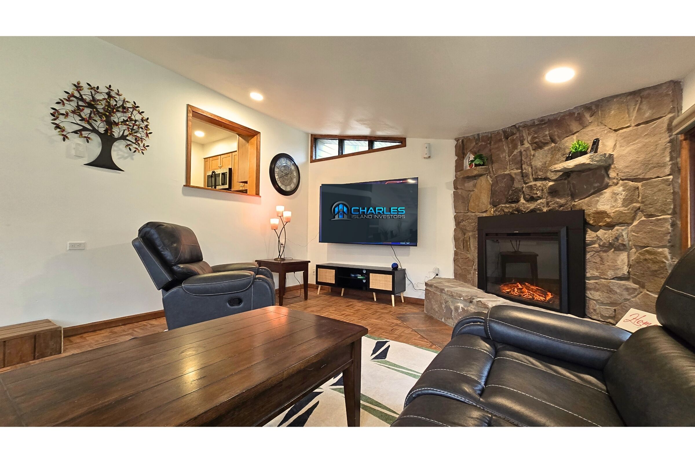 Cozy living room with stone fireplace, leather recliners, and large smart TV