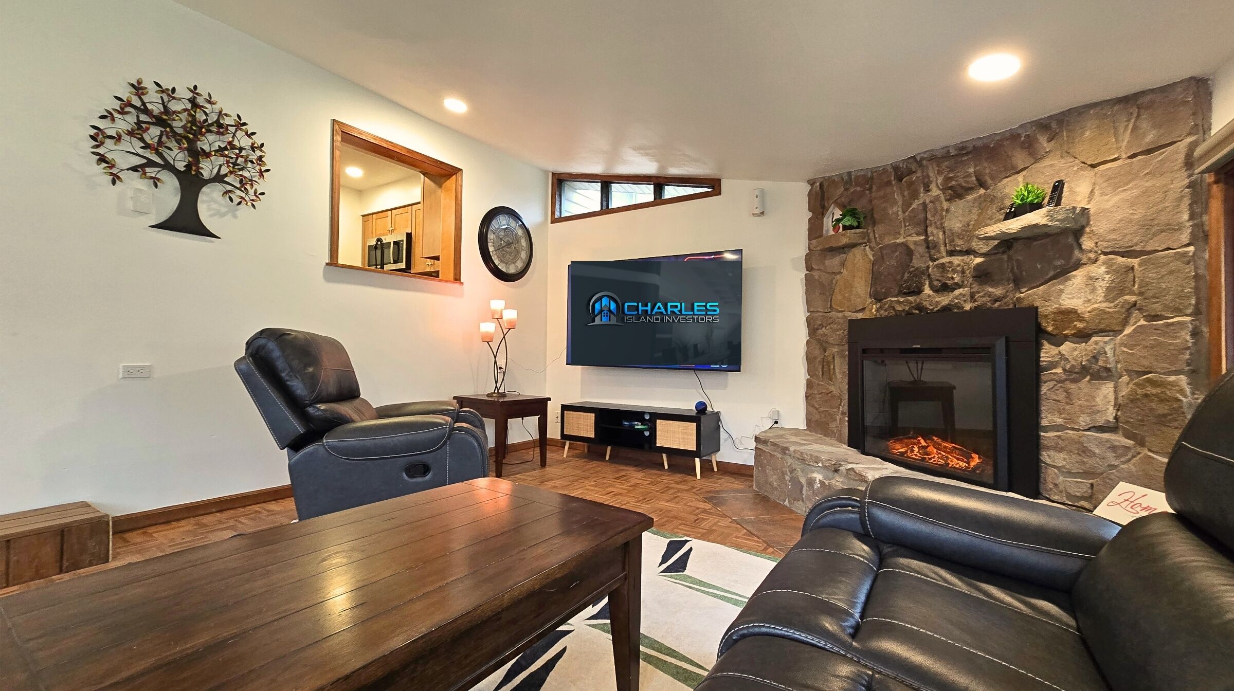 Cozy living room with stone fireplace, leather recliners, and large smart TV