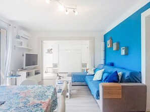 A modern room with a bed, a sofa, a TV, and a desk. - El Rayo del Sol by Interhome (Six Fours)
