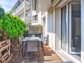 Eine Terrasse im Freien mit Tisch und Stühlen, einem Holzzaun und einem Gebäude mit Balkonen.