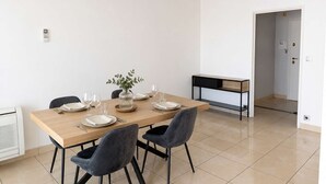 A modern dining room with a wooden table, four chairs, and a vase with greenery. - SAINT-RAPHAËL CITY CENTER – BEACH WITHIN WALKING DISTANCE – COMFORTABLE 1-BEDROOM APARTMENT (ST RAPHAEL)