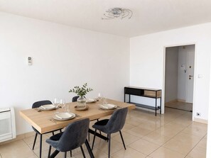Ein stilvolles Esszimmer mit einem Holztisch, vier Stühlen und einer Vase mit Grünpflanzen.
