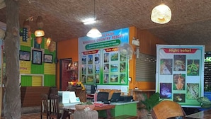 A rustic interior with a wooden ceiling, a signboard for Khaosok Country Resort, a desk with a computer, chairs, and a bench. - Khao Sok Country Resort (Phanom)