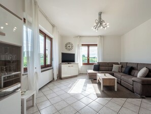 Ein Wohnzimmer mit einer Couch, einem Fernseher und einer Wanduhr.