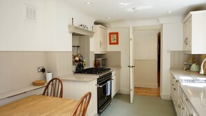 A compact kitchen with white cabinetry, a stove, and a microwave. - Cozy Victorian 1BDR Garden Flat in Greenwich (Greater London)