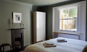 Ein Hotelzimmer mit Bett, Kamin, Kleiderschrank und Fenster mit Blick nach draußen.