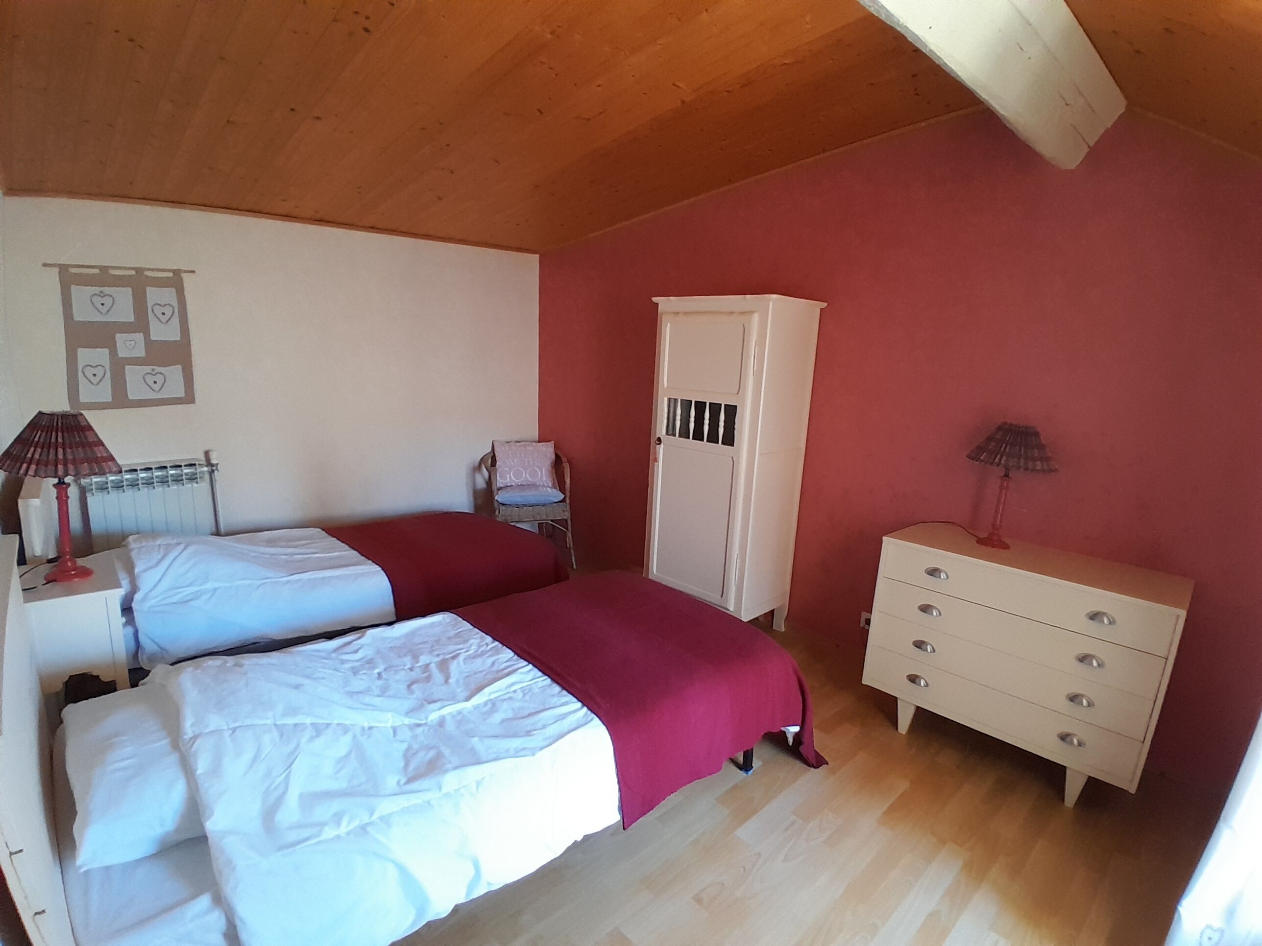 Une chambre avec deux lits, une armoire, une chaise et un radiateur.