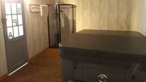 Ett rum med en stor möbel i mörk färg, en dörr med ett frostat glasparti och en duschhörna.