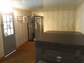 Ein Zimmer mit einem großen, dunkel gefärbten Möbelstück, einer Tür mit Milchglasfenster und einem Duschbereich.