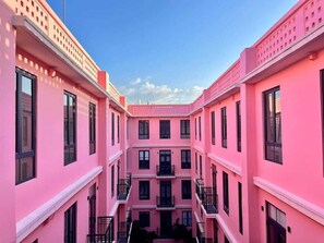 A pink multi-story building with balconies and windows. - Modern Condo in Casco Viejo w/ Private Balcony (Panamá)