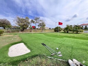 Un parcours de golf bien entretenu, doté d’un bunker de sable, de clubs de golf et d’un drapeau.