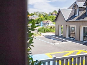 A building with a sloped roof, a parking area with yellow directional arrows, and a view of houses in the background. - Villerville by Interhome (Villerville)