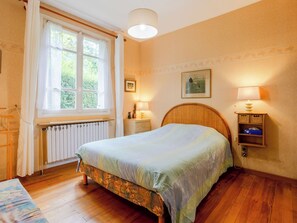 A bedroom with a bed, a window, a radiator, bedside lamps, and a small table. - Villerville by Interhome (Villerville)