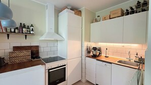 A modern kitchen with white cabinets, a Bosch oven, a coffee machine, and a built-in dishwasher. - City Apartment in Stengade with 1 bedrooms sleeps 2 (Stengade)