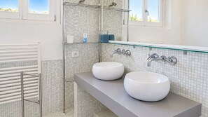 A bathroom with two white sinks, a glass shower enclosure, and a towel rack. - Camera tripla del Geco natura e relax (Marciana)