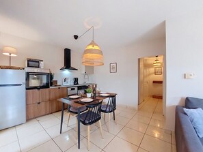 Eine moderne Küche mit Essbereich, inklusive Tisch mit Stühlen, einem Kühlschrank, einem Backofen, einer Mikrowelle und einer Pendelleuchte.