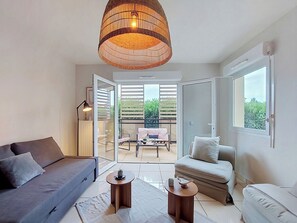 A modern living room with a sofa, a coffee table, a side table, and a hanging light fixture. - l'Etoile du Sud by Interhome (Saint Laurent de la Salanque)
