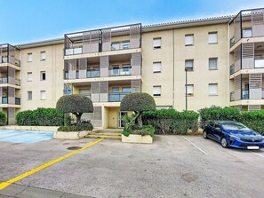 Ein mehrgeschossiges Wohngebäude mit Balkonen, einem Parkplatz und gepflegter Außenanlage.