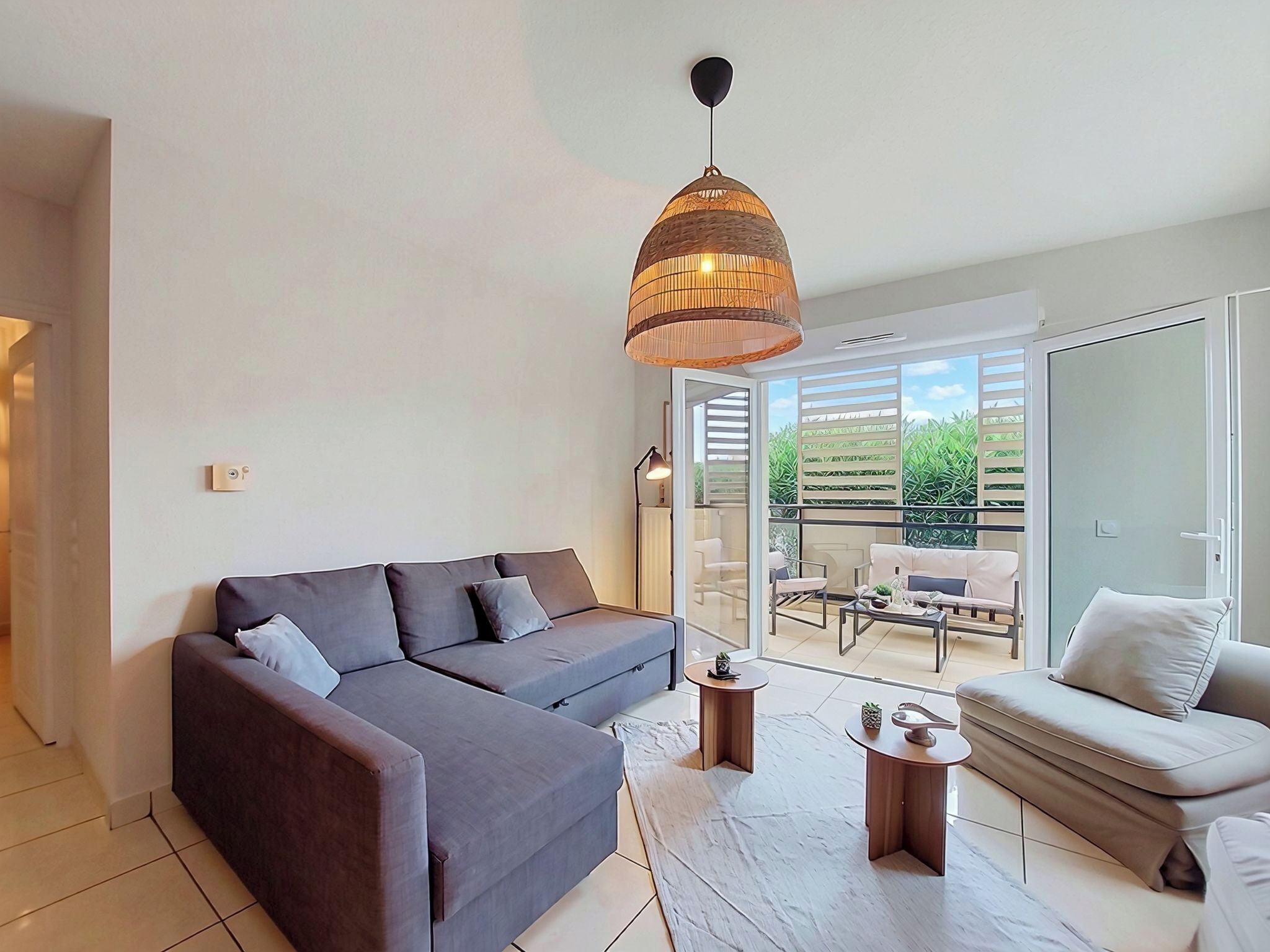 A modern living room with a grey sofa, a smaller sofa, a coffee table, and a hanging light fixture.