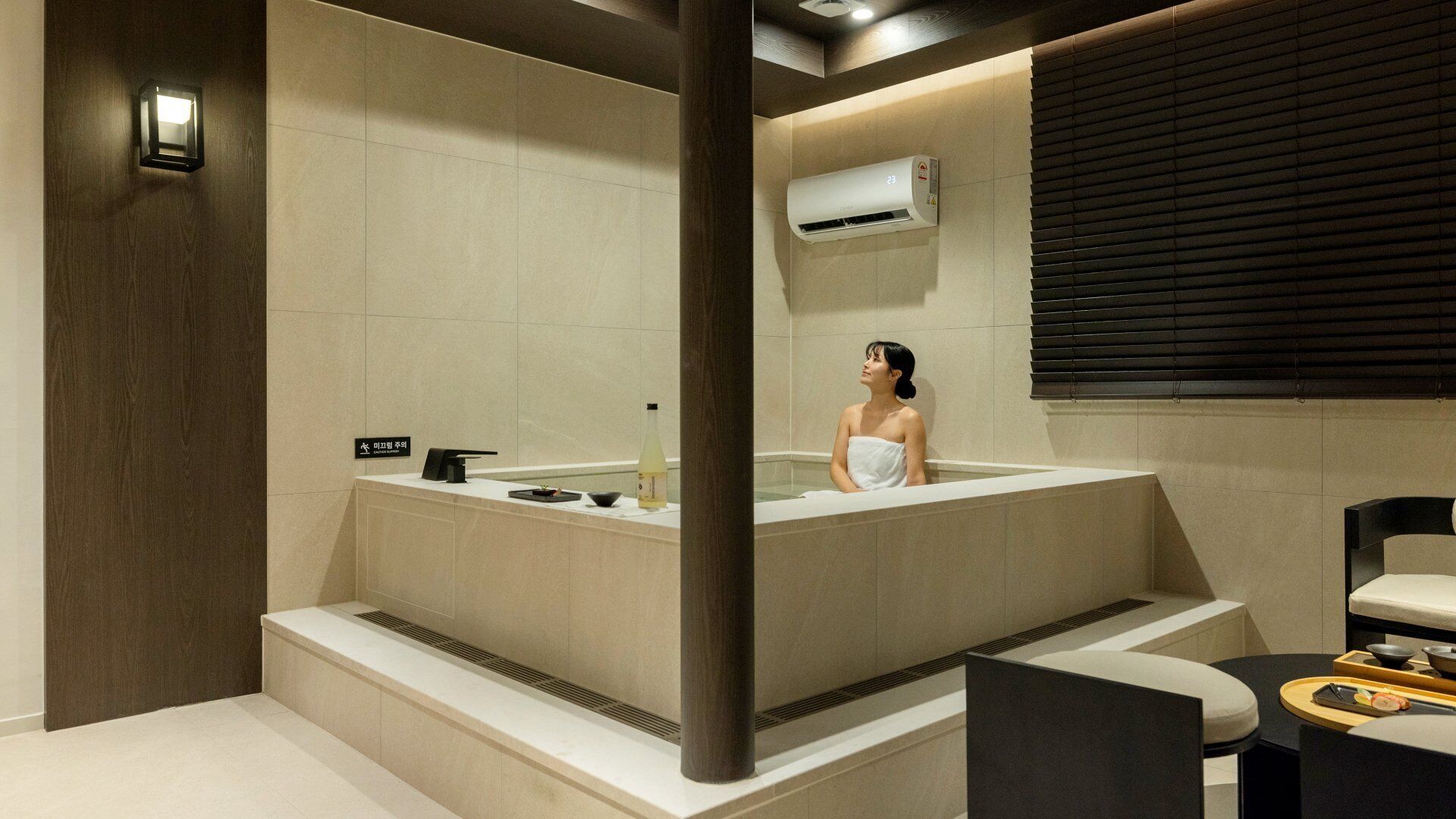 Une salle de bain moderne avec une baignoire, un porte-serviettes, une bouteille et une petite table avec un plateau.