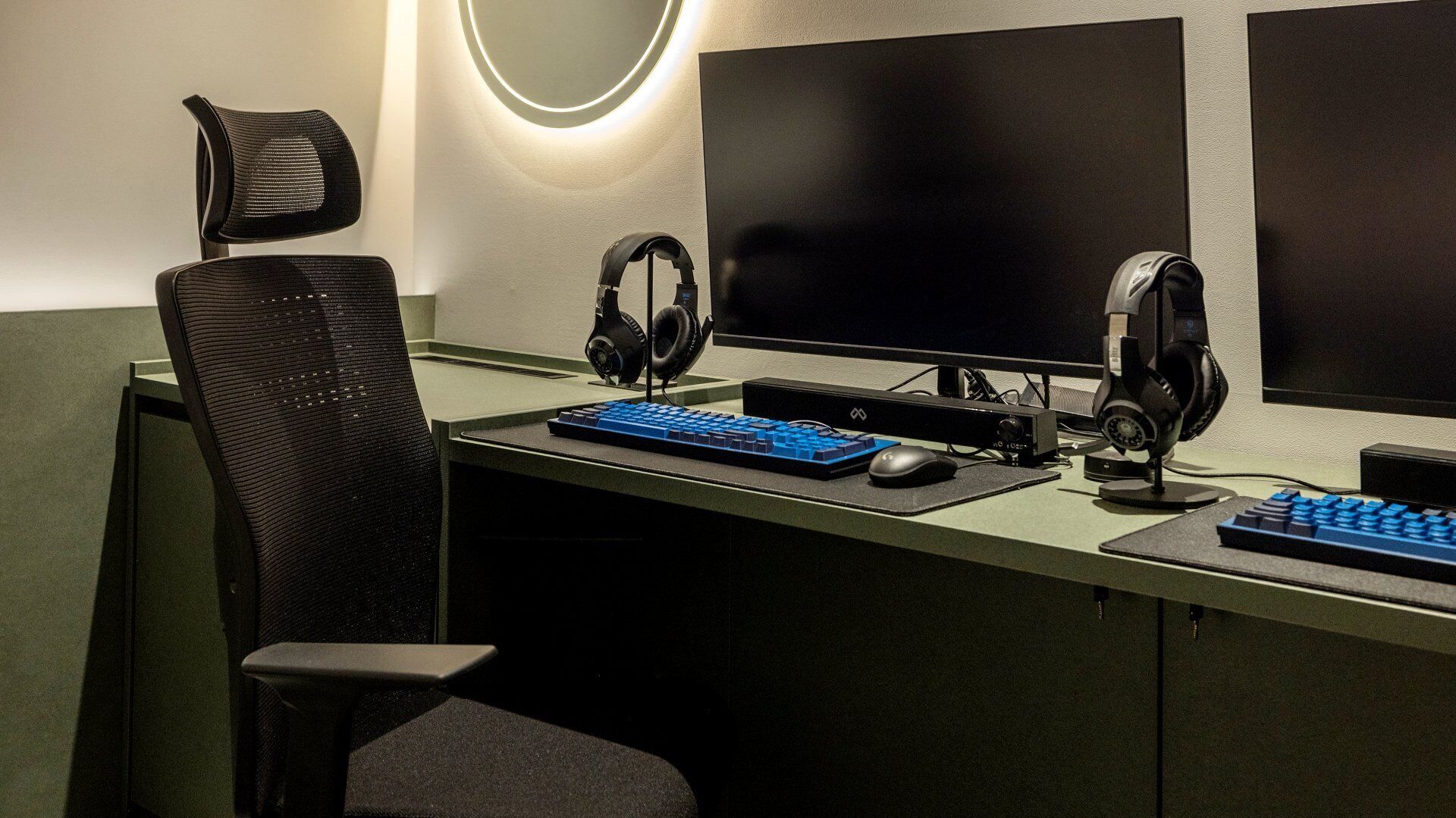 A modern office setup with a desk, two monitors, a keyboard, headphones, and a chair.