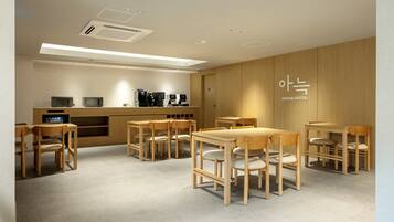 A hotel room with wooden furniture, a kitchenette, and a ceiling with recessed lighting.
