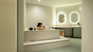 Un baño moderno con una bañera independiente, un tocador con espejo y un inodoro.
