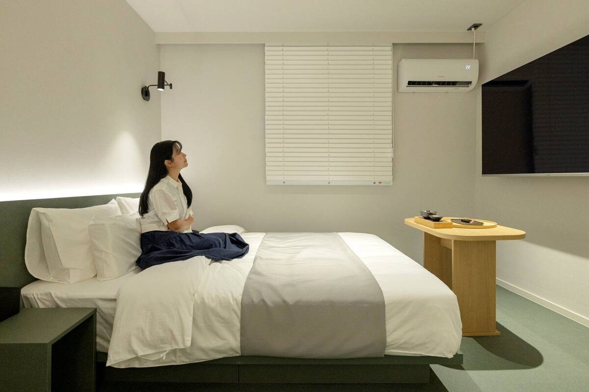 Une chambre d’hôtel équipée d’un lit, d’une table de chevet et d’un climatiseur fixé au mur.
