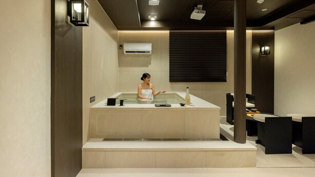Un cuarto de spa con una bañera, una toalla y una botella sobre el mostrador.