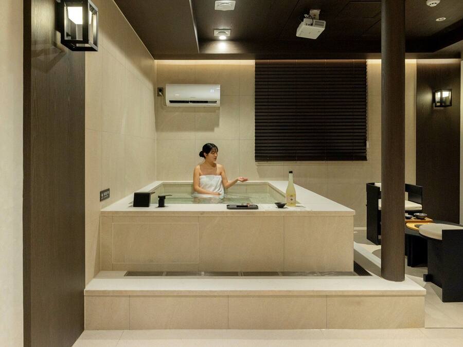 A spa room with a bathtub, a towel, and a bottle on the counter.