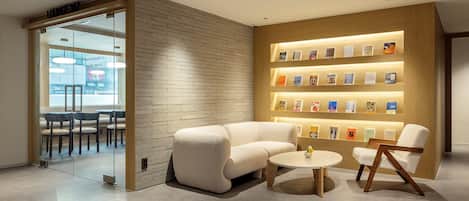 A modern lounge area with a brick wall, a sofa, a coffee table, and a bookshelf with books.